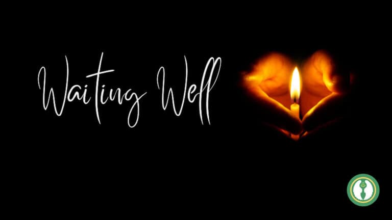 Waiting well, a lit candle in the dark, cupped by two hands.