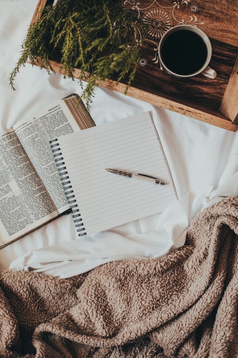A photo of an open bible and an empty note pad with pen.
