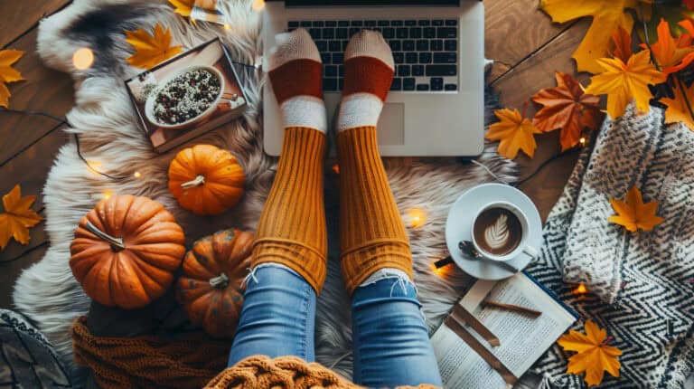 Autumn scene with a laptop, pumpkins and someone's feet with warm cosy socks