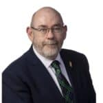Jim McManus, man wearing a suit and tie. He is wearing glasses and has a bit of a beard and moustache