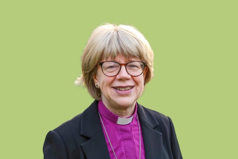 A photograph of Bishop Sarah Mullally in front of a green background