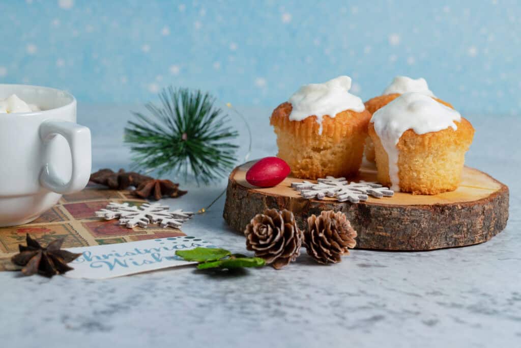 Creamy muffins on a wooden surface with a mug and a Christmas card