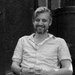 Black and white photo of a man wearing a white shirt, he's sitting down