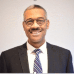 A person wearing glasses and a suit.